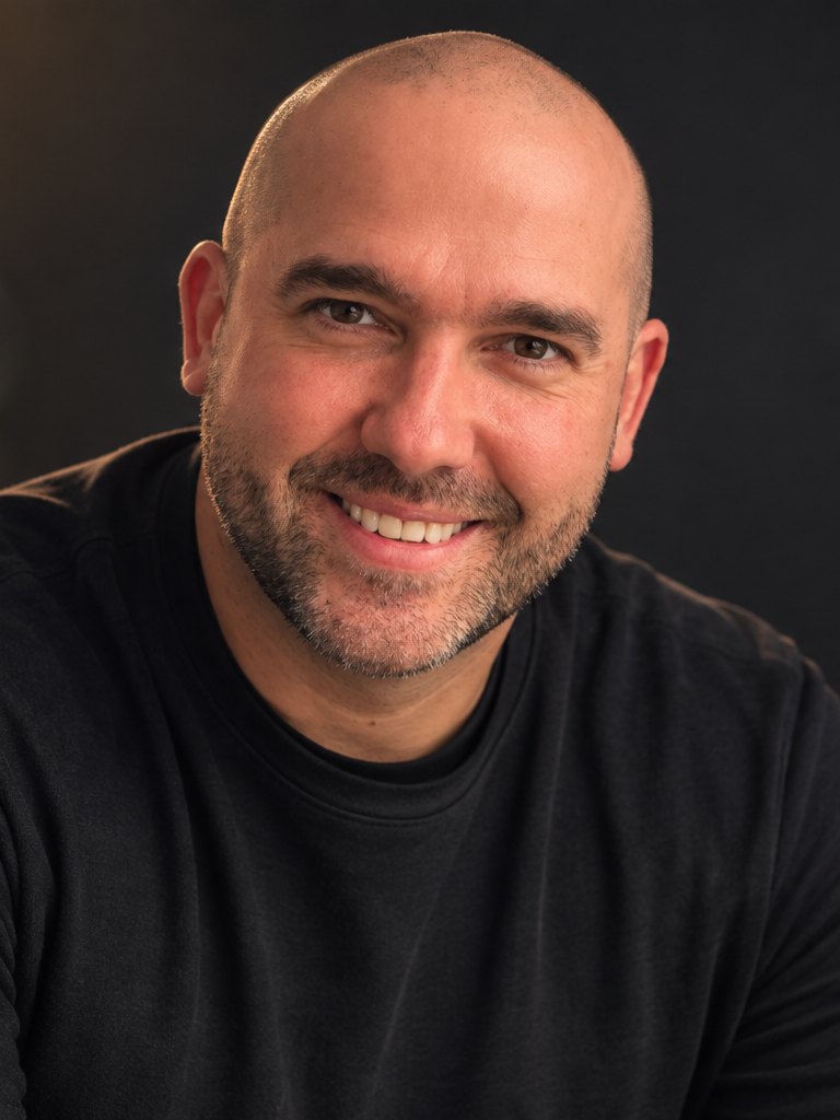 Rob, founder of Layer Logic Studio, smiling in a black sweater against a dark wall